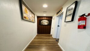 Un couloir doté d’un plancher en bois, de murs blancs et d’un extincteur fixé au mur.