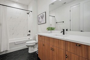 Un bagno moderno con una vasca da bagno bianca, un water e un mobile lavabo con specchio.