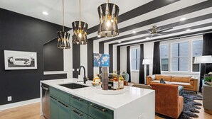 Uma cozinha moderna com ilha central, teto listrado em preto e branco e iluminação pendente.