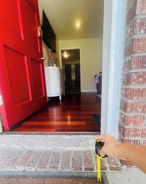 A red door leading to a hallway with a white console table and a brick wall. - 3 BR Great Discounts, Good Vibes Only, South Coast Home - Clean & Safe (Ladson)
