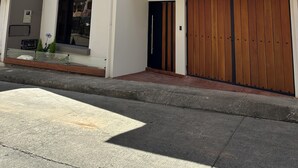 En toetages boligbygning med fladt tag, garageport foran og en lille balkon med plantekasser.