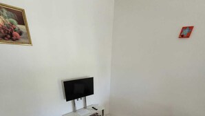Una sala de estar con un sofá, un televisor, una mesita con revistas y una alfombra.