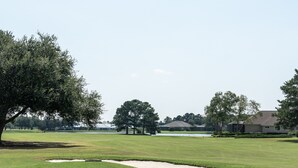 A golf course with sand bunkers, trees, and houses in the background. - Villa C-Villa Ensuite (Gulfshores)