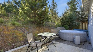 Un patio al aire libre con mesa y sillas, un jacuzzi inflable grande y árboles circundantes.