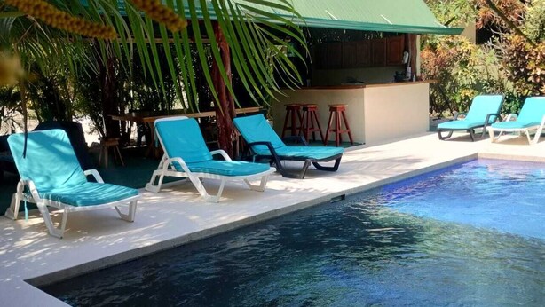 A pool area with lounge chairs and a bar. - Casa Mango Two-bedroom home a short 4-minutes walk from the ocean, w/ pool & BBQ (Guanacaste Province)