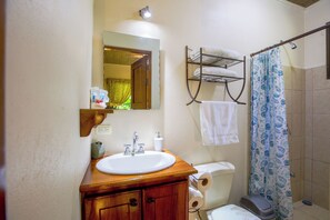 Une salle de bain avec un meuble-lavabo en bois, un évier, un miroir, un porte-serviettes et un rideau de douche.