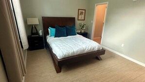 Une chambre à coucher avec un lit en bois, une table de chevet, une lampe et une porte.