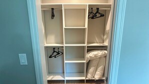 A walk-in closet with multiple shelves and hanging space, light-colored walls, and a wooden floor. - Central City Condominiums #203 2BR/2BA (Sarasota)