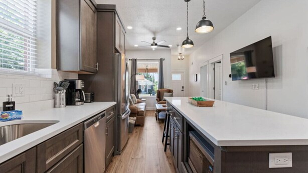 A modern kitchen with dark wood cabinets, stainless steel appliances, and a large island. - Historic 1907 SLC Victorian - Hot Tub - Firepits - (South Salt Lake City)