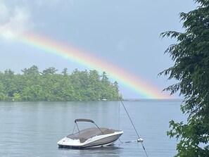 Un barco sobre aguas tranquilas con un arcoíris al fondo.