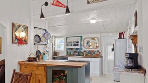 A kitchen with a wooden island, hanging pots, and a coffee maker. - Camp Red Lodge - Cozy & Convenient (Red Lodge)