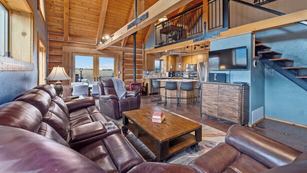A spacious living area with a leather sofa, wooden coffee table, and a kitchen in the background. - Henry's Hideaway Cabin (Red Lodge)