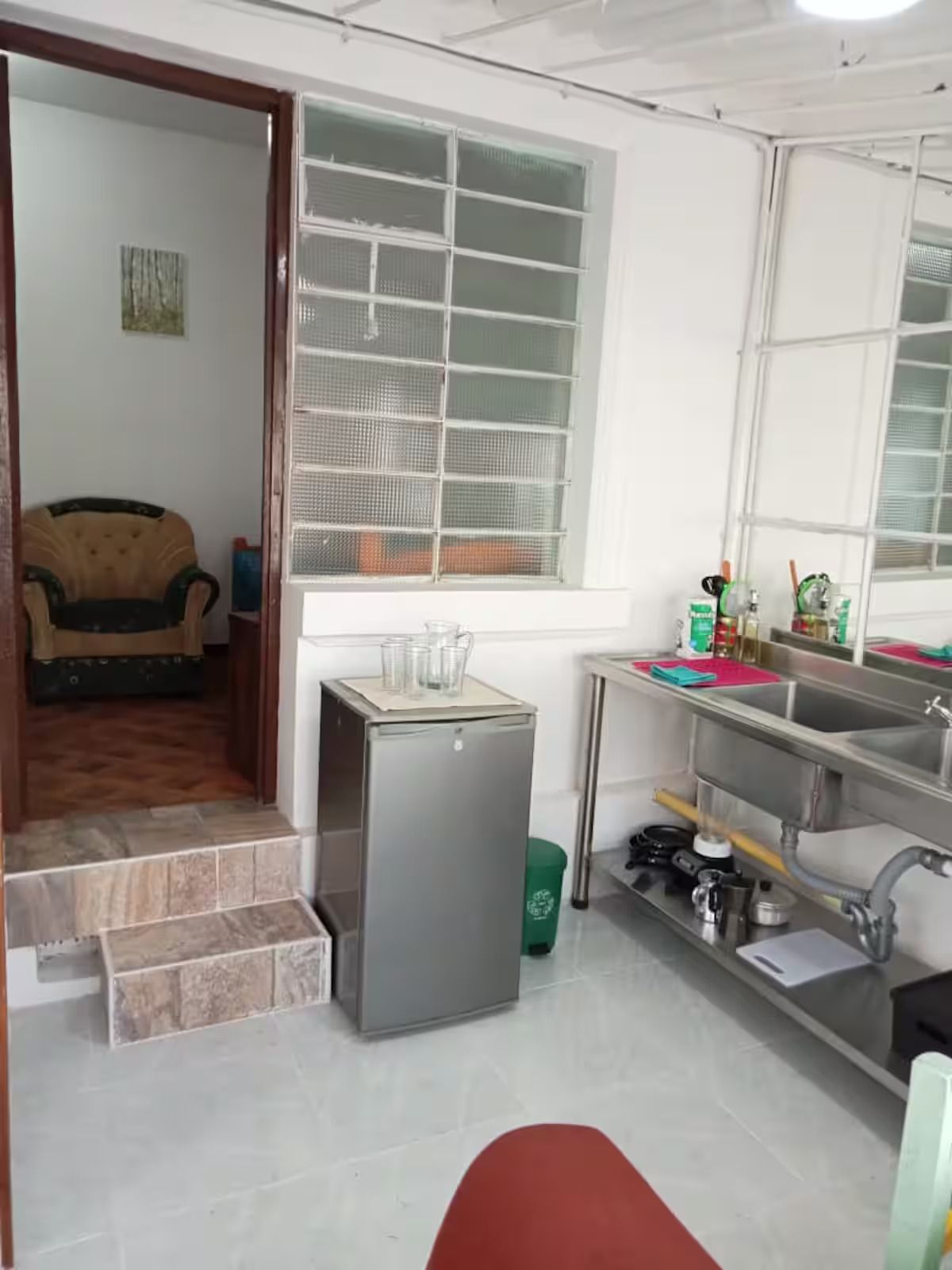A compact kitchen with a refrigerator, sink, and window.