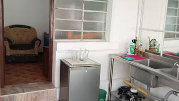 A compact kitchen with a refrigerator, sink, and window.