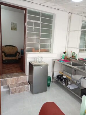 A compact kitchen with a refrigerator, sink, and window. - Hospedaje La Tierrita Bogotá (Bogotá)