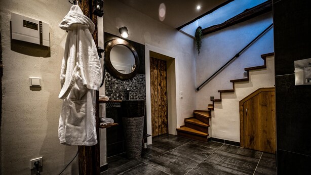 Un baño moderno con un perchero, un espejo, una escalera de madera y suelo de baldosas.