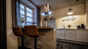 Una cocina moderna con dos taburetes de bar, una lámpara colgante y un salpicadero con la palabra "witalo" en la pared.