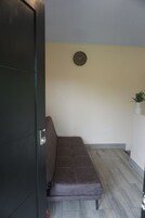 Una habitación con un sofá marrón, un reloj de pared y una pequeña planta en un estante.