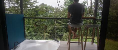 Uma pessoa parada em uma varanda com vista para um jardim exuberante.