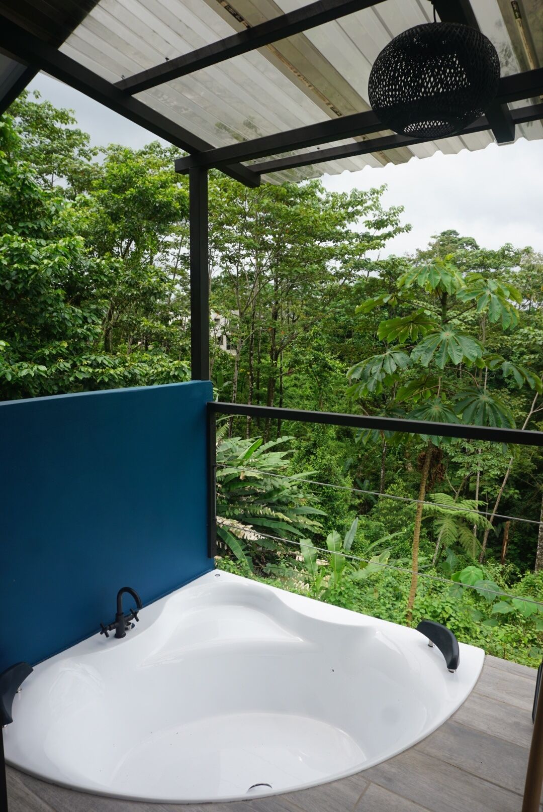 A hot tub under a covered area with a view of dense greenery.