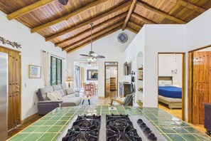 A kitchen with a tiled backsplash, a ceiling fan, and a dining area with a table and chairs.