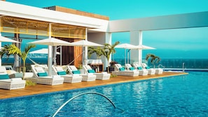 A poolside area with lounge chairs and umbrellas, a wooden deck, and a view of the ocean. - Beachfront Grand Luxxe Spa Suite 3 BEDRM (Nuevo Nayarit)
