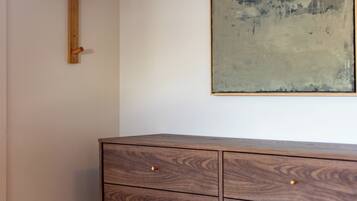 A wooden dresser with drawers, a wooden coat rack, and a large abstract painting on the wall.