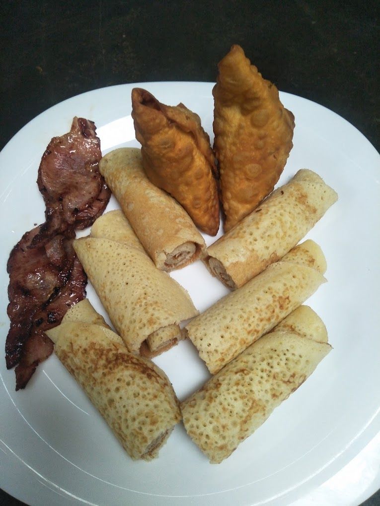 A plate with various food items including a piece of meat and several rolled pastries.