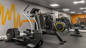 Ein Fitnessraum mit unterschiedlichen Trainingsgeräten, darunter Laufband, Kraftgeräte und eine Trainingsbank.