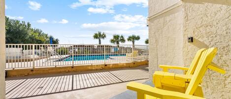 A pool area with a wooden deck, a yellow chair, and a fenced pool.