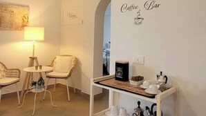 Een gezellig koffiehoekje met rieten stoelen, een kleine ronde tafel en een koffiehoek met bekers en een waterkoker.