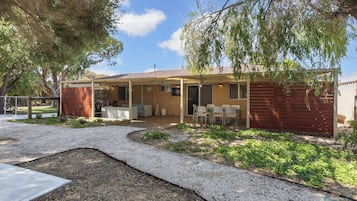 A two-story house with a covered patio, a fenced yard, and a gravel driveway.