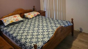 Un dormitorio con cama de madera, ventilador de techo y ventana con persianas.