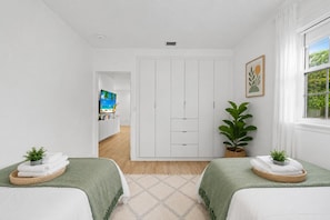 A hotel room with a bed, a TV, a wardrobe, and a window with curtains.