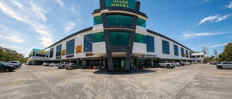 Un hotel con un letrero llamativo, varios espacios de estacionamiento y un cielo despejado.