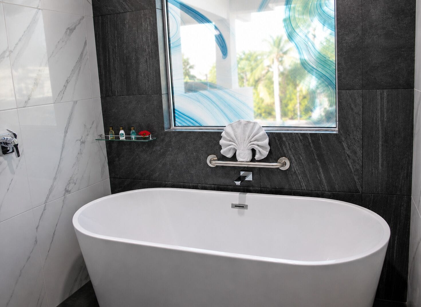 A modern bathroom with a freestanding bathtub, a glass shelf with toiletries, and a decorative shell.