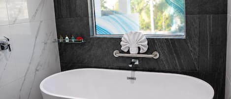 A modern bathroom with a freestanding bathtub, a glass shelf with toiletries, and a decorative shell.