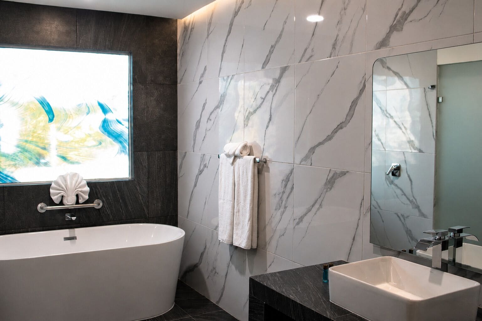 A modern bathroom with a freestanding bathtub, a vanity with a sink, and a large mirror.
