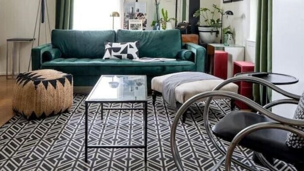 Una sala de estar moderna con un sofá verde, alfombra estampada y una lámpara de araña original.