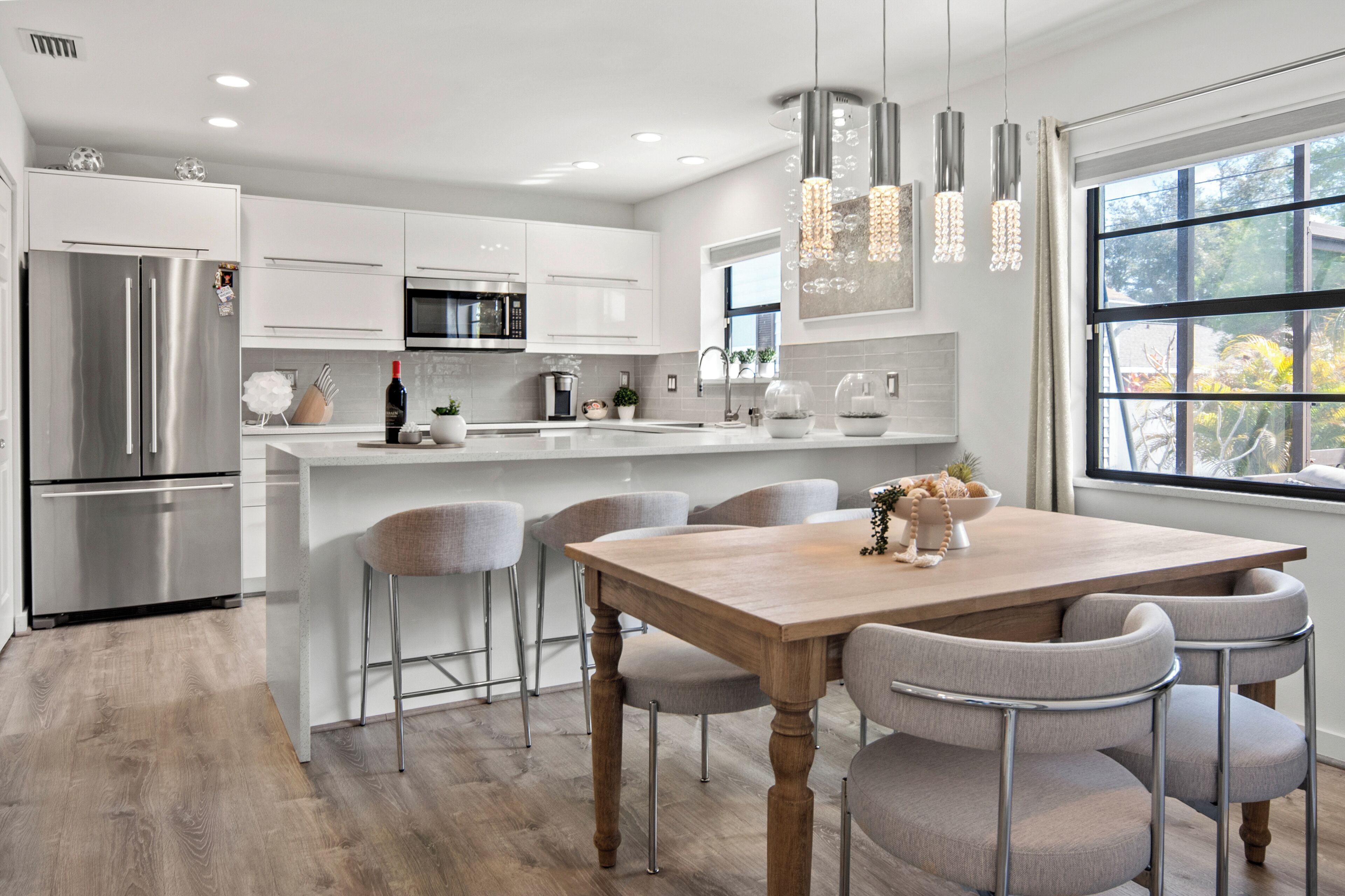 Una cocina moderna con una isla central, electrodomésticos de acero inoxidable e iluminación colgante.