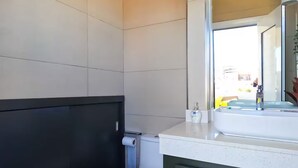 Ein modernes Badezimmer mit einer weißen Toilette, dunklen Schränken und einem großen Spiegel über dem Waschbecken.