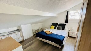 Een slaapkamer met een bed, nachtkastjes, een bureau en een raam.