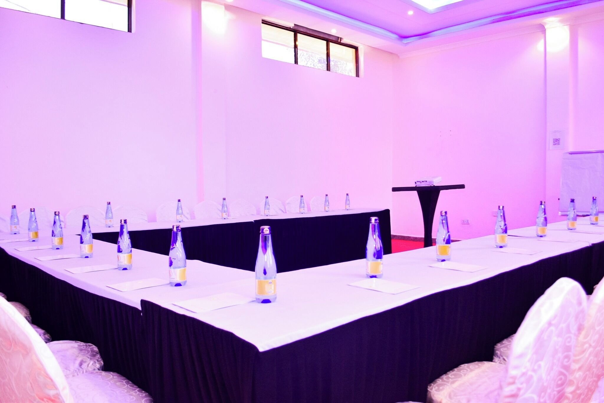 Uma sala de conferências com uma mesa comprida, cadeiras e um púlpito.