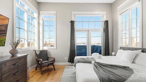 Ein Schlafzimmer mit einem großen Bett, einem Sessel, einem Schminktisch und einem Fenster mit Vorhängen.