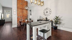 Una cocina moderna con pared de ladrillo decorativa, un reloj grande y una zona de bar.
