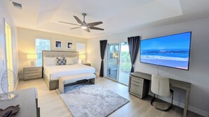 Una camera da letto con un letto, comodini, una TV, una scrivania e un balcone vista mare.