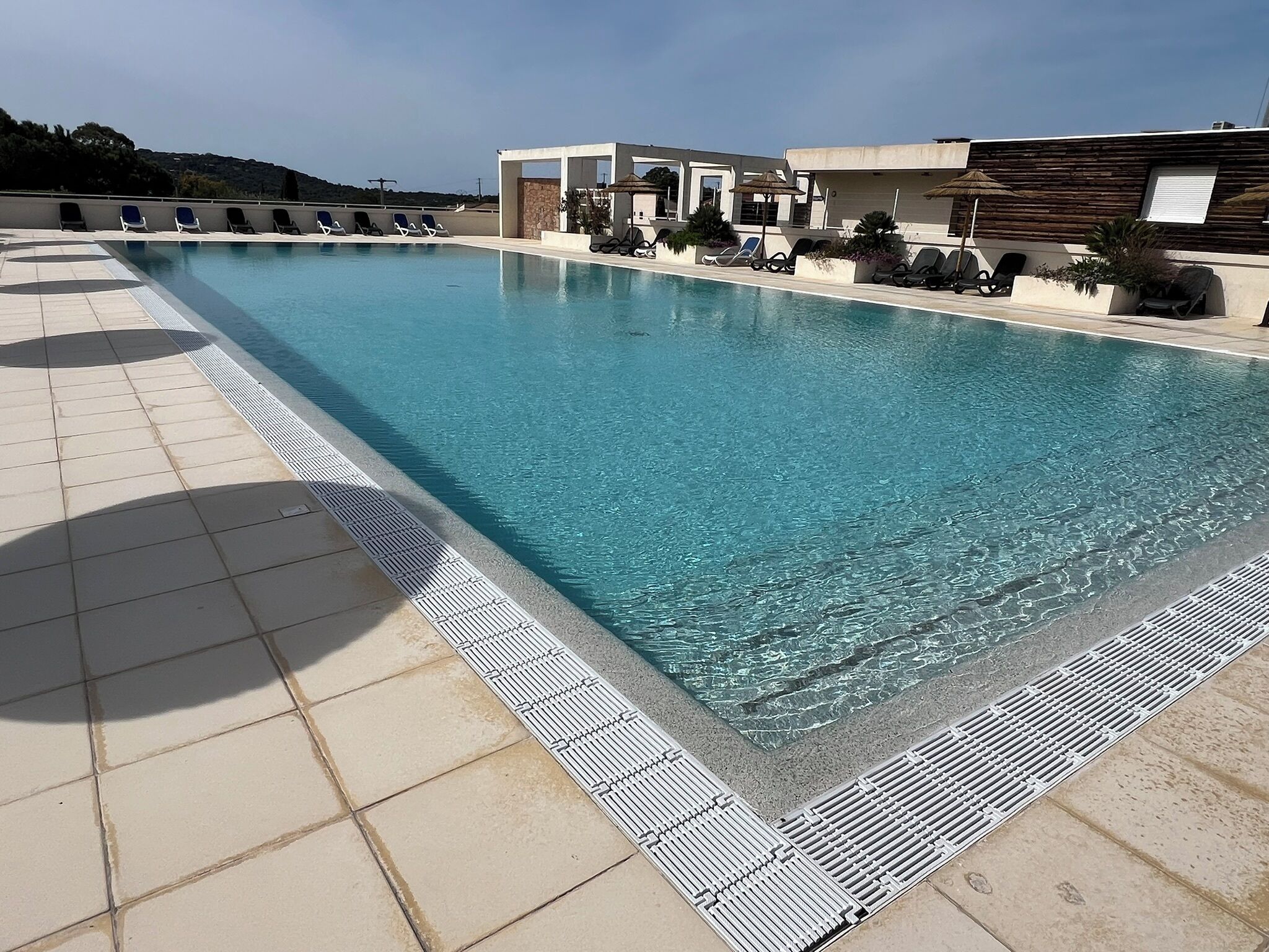 A rectangular swimming pool with a tiled deck and a safety edge.