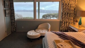 A bedroom with a large window, a bed, a chair, and a bedside table. - Furnished 30 to 60 day rental - Feb/March - Architectural Gem with Bay Views (Sausalito)