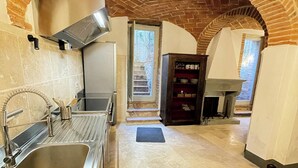 Eine Küche mit Ziegelbogen, Spüle aus Edelstahl und Holzschrank.