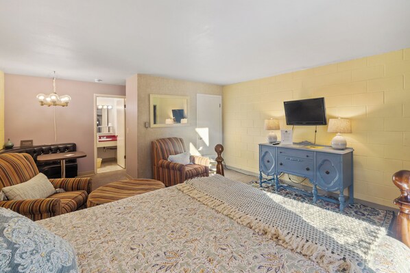A hotel room with a large bed, a television, a dresser, a chair, and a small table. - Château Rouge 104 ~ Continental Cottage (Red Lodge)